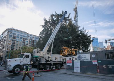 A 60 ton crane hoists the CME 55 LCX drill rig from the street toward the drill site.